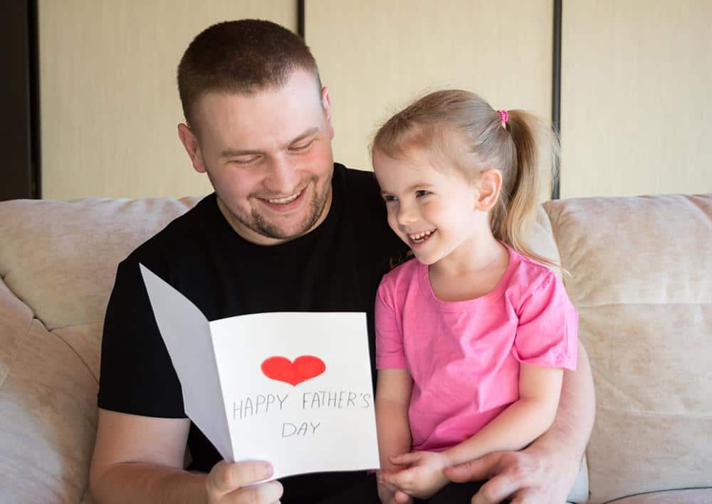 Father and daughter smiling and looking at a card